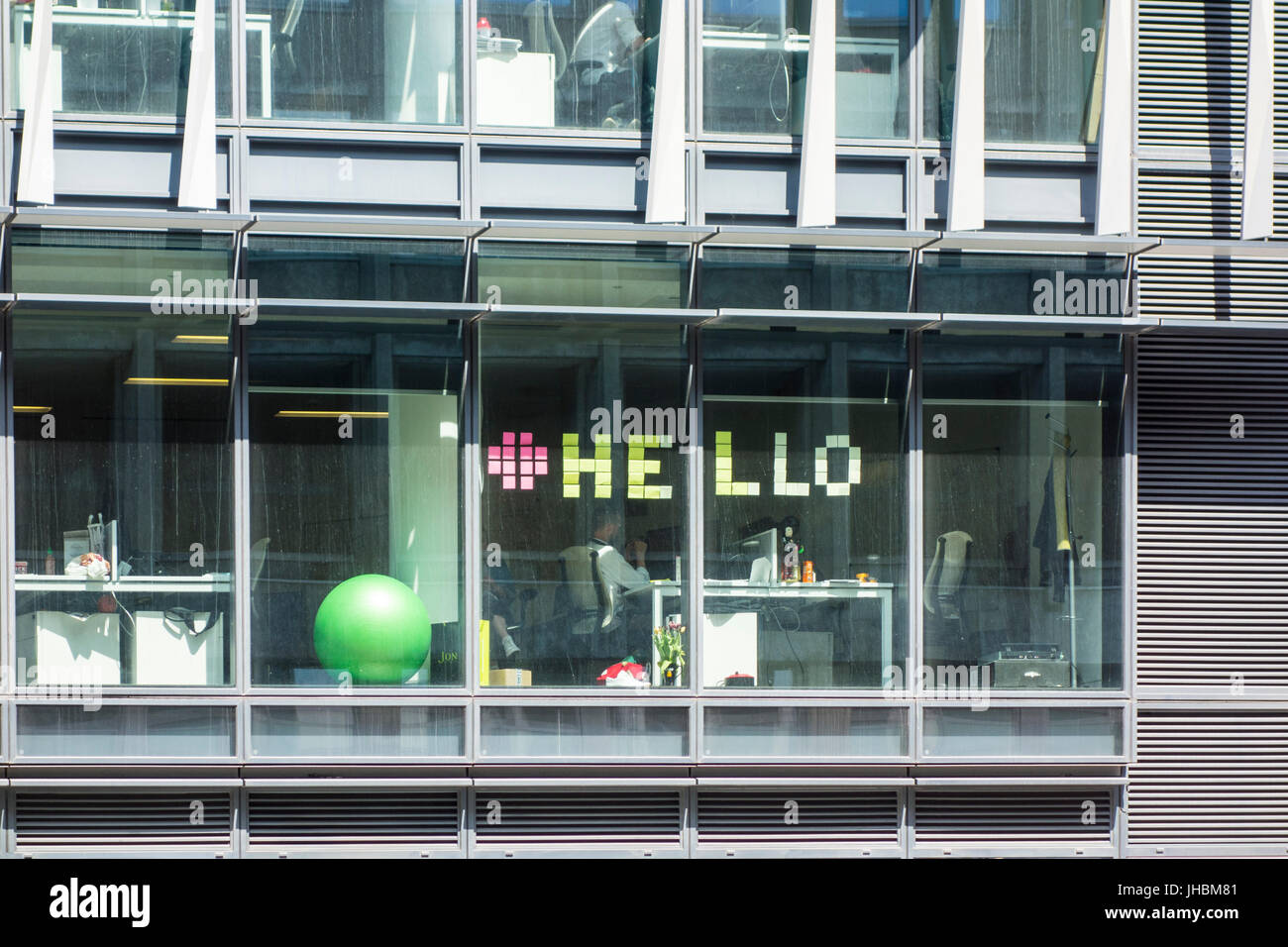 Trabajador de oficina hechizos 'hola' con post-it notes en ventana, London, UK Foto de stock