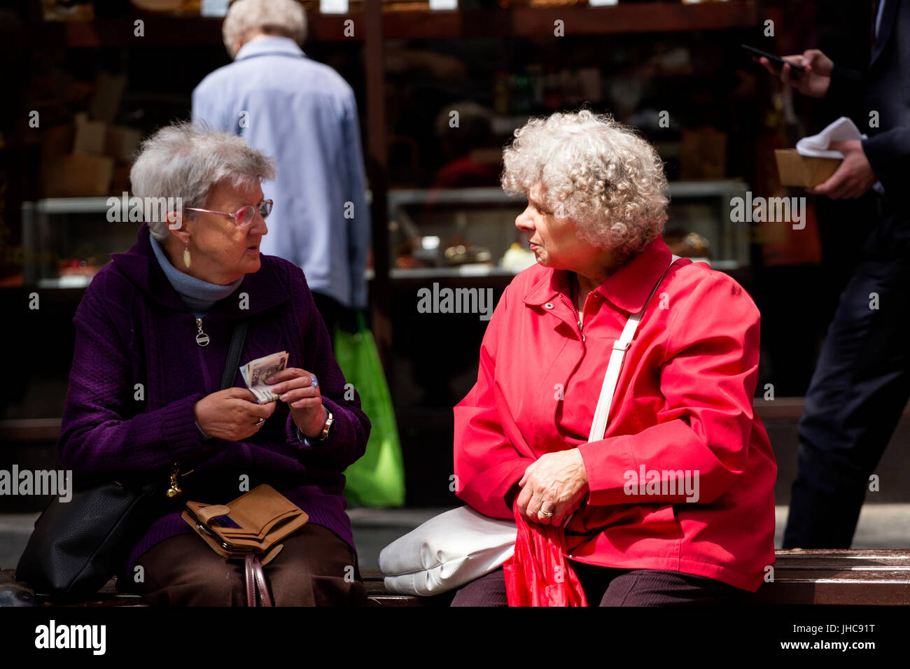 Dos mujeres de edad pensionistas sentado en un asiento de charlar sobre sus fondos de pensiones en Dundee, Reino Unido Foto de stock