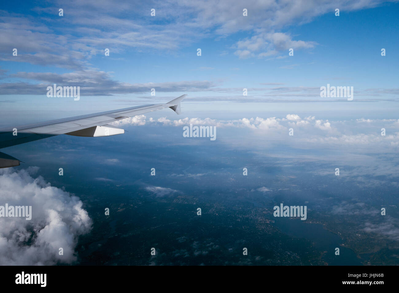 Por encima de las nubes volando alto en vista de la ventana del avión Foto de stock