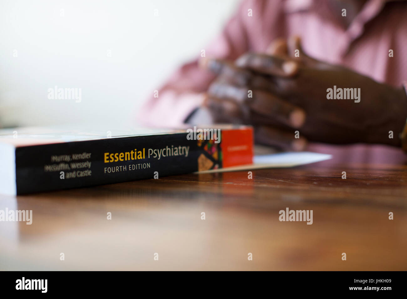 Un libro llamado esencial Psiquiatría sentado delante de alguien en un escritorio. Foto de stock