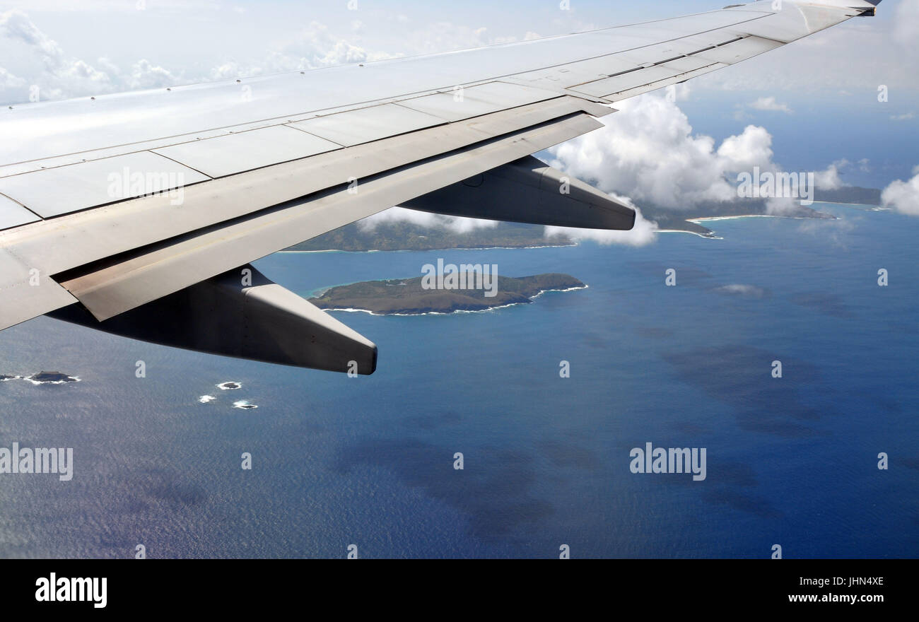 Parte del ala de un avión con nubes, islas y el mar. Foto de stock