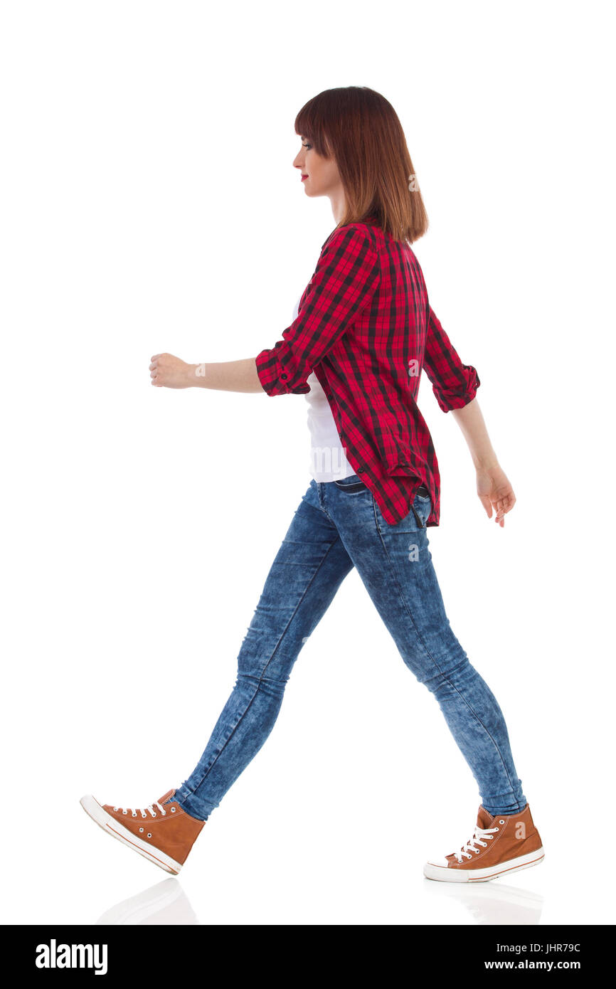 Mujer en rojo de leñadores de camisa, pantalones vaqueros y zapatillas  marrones y caminar mirando a otro lado. Vista lateral. Longitud total  studio shot aislado en blanco Fotografía de stock - Alamy