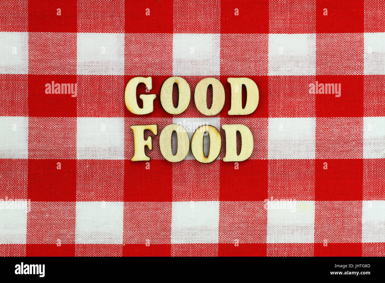 Buena comida, escrito con letras de madera en tela de cuadros rojo y blanco Foto de stock