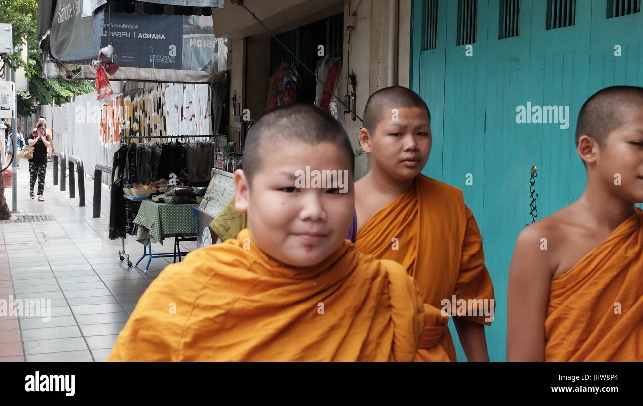 El monaquismo joven túnica de color naranja Azafrán Escuela Budista Theravada Wat Yannawa Boy monjes caminando por la calle Sathorn Bangkok Thailand Foto de stock