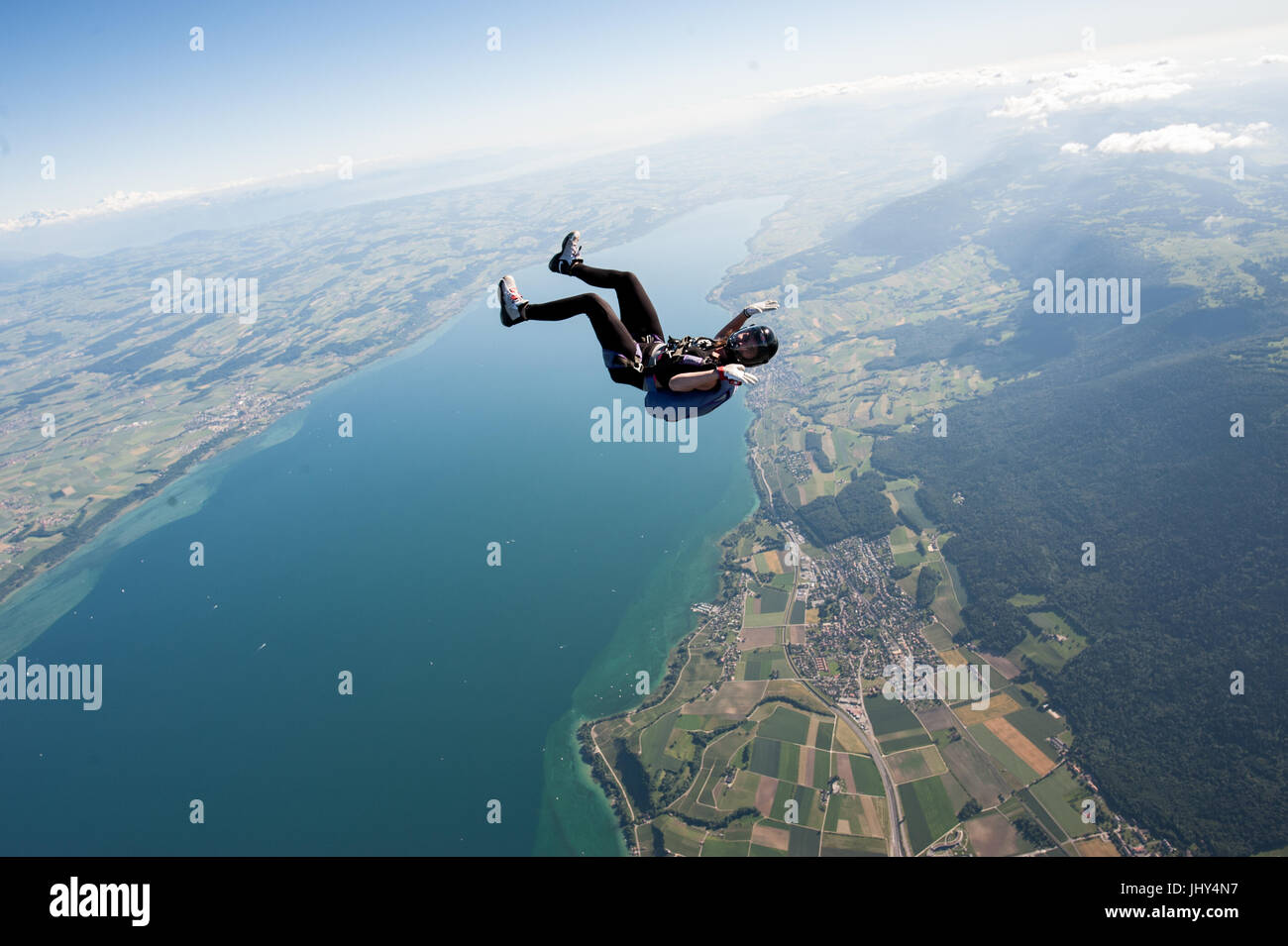 Una mujer haciendo un divertido skydive encima del lago Neuchatel en Suiza Foto de stock