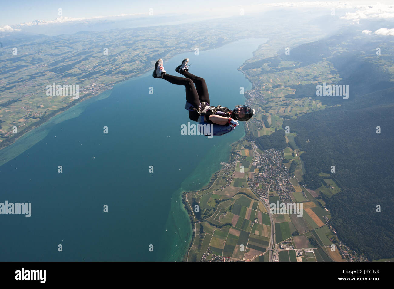 Una mujer haciendo un divertido skydive encima del lago Neuchatel en Suiza Foto de stock