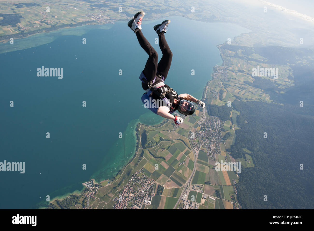 Una mujer haciendo un divertido skydive encima del lago Neuchatel en Suiza Foto de stock