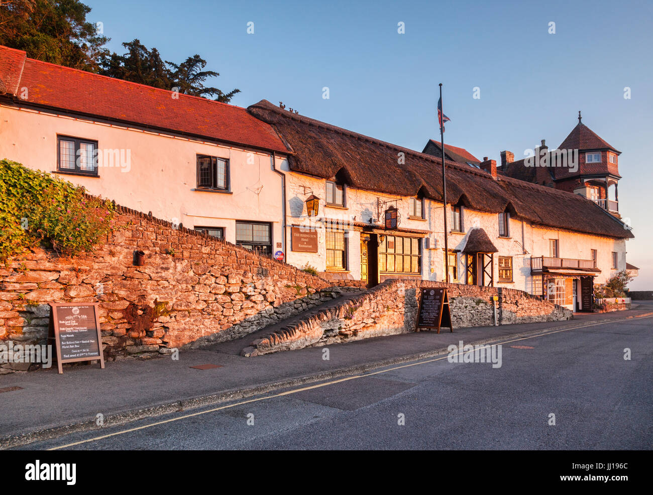 19 de junio de 2017: Lynmouth Devon, Inglaterra, Reino Unido - las cabañas antiguas de Mars Hill, con el sol naciente se reflejan en los vidrios de la Rising Sun Hotel. Foto de stock