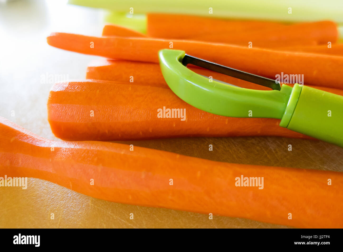 Un pelador de zanahoria verde sentado en una pila de zanahorias en una  tabla para cortar Fotografía de stock - Alamy