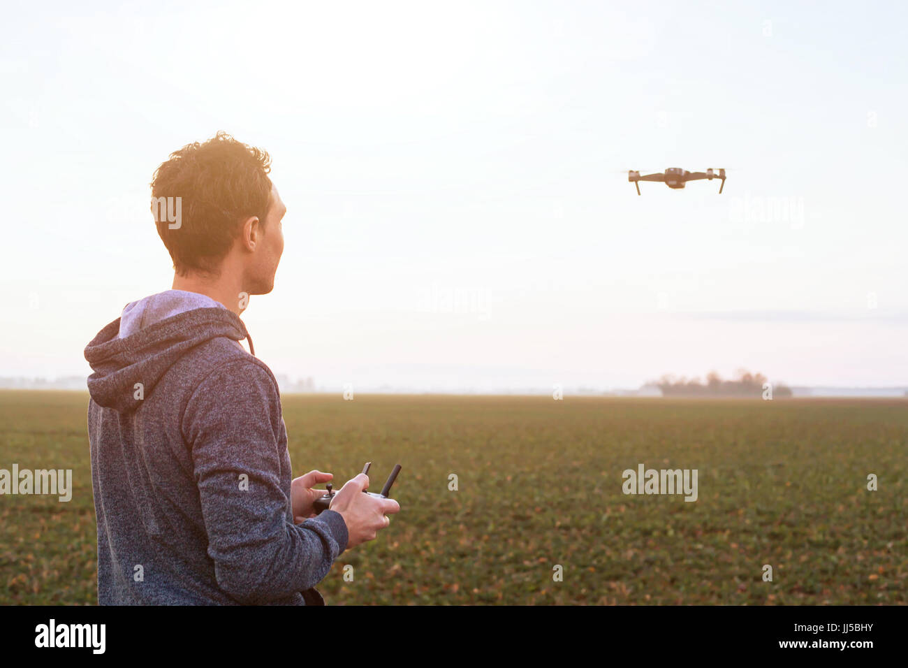 Hombre drone experimental al atardecer campo, tecnología de UAV antecedentes Foto de stock