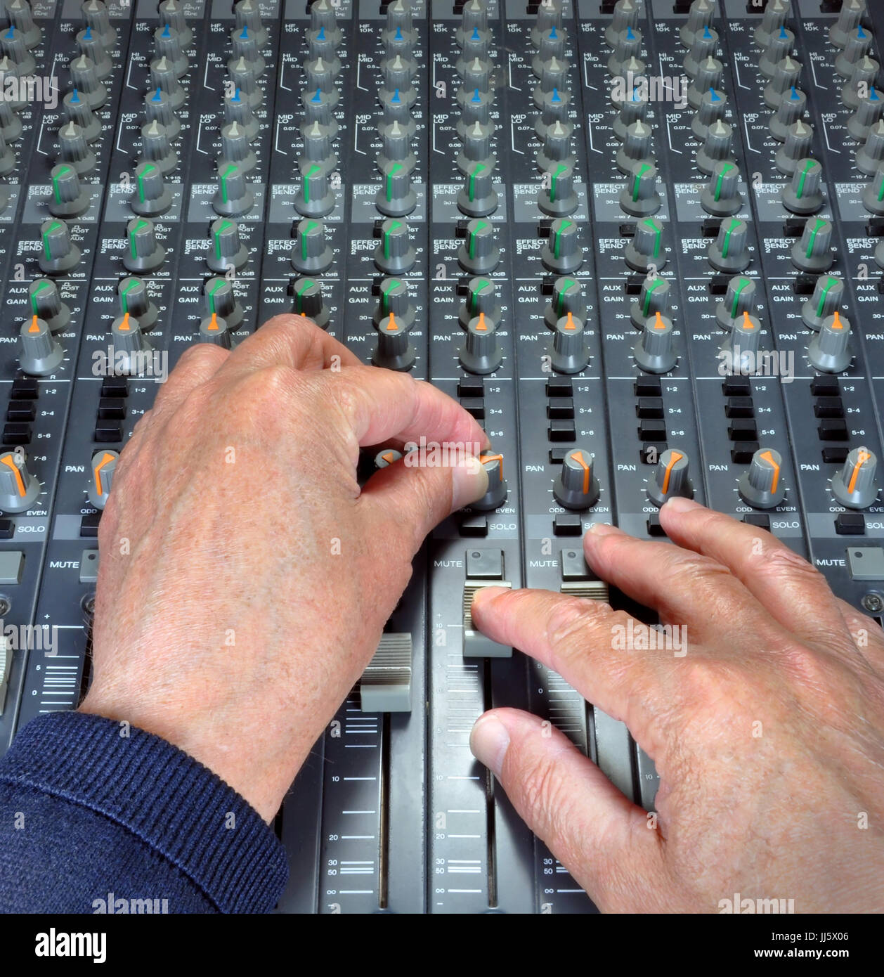 Manos expertas utilizando los deslizadores, los botones y diales analógicos en una mesa de mezclas y grabaciones de música en un estudio. Foto de stock