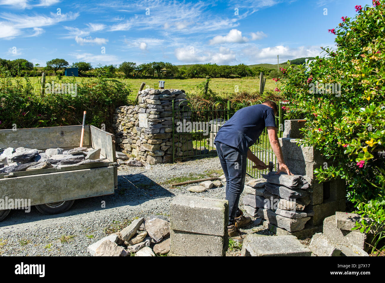 Albañil construye un muro de piedra seca tradicional en el oeste de Cork, Irlanda con espacio de copia. Foto de stock