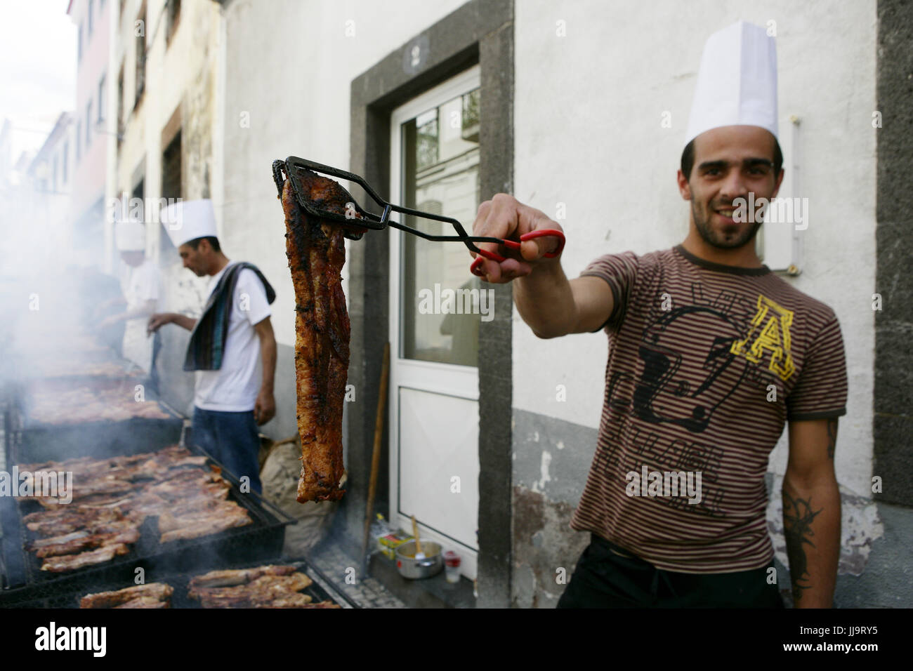 Un hombre joven ofrece carne de la parrilla en la calle, Funchal, Madeira, Portugal Foto de stock