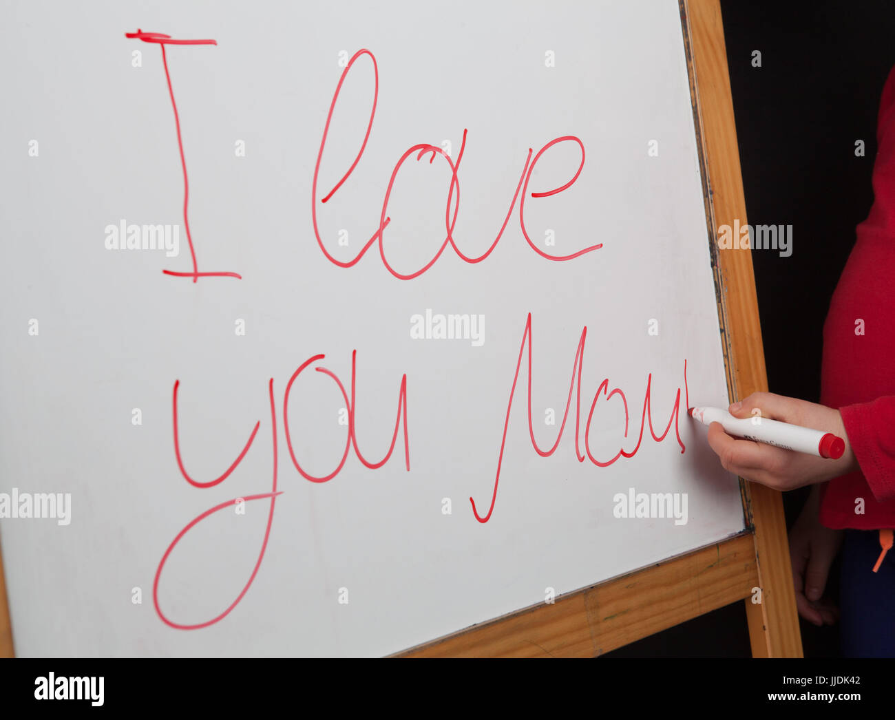 Palabras I love you Mom writeen en pizarra con childs mano sujetando el marcador de pizarra Foto de stock