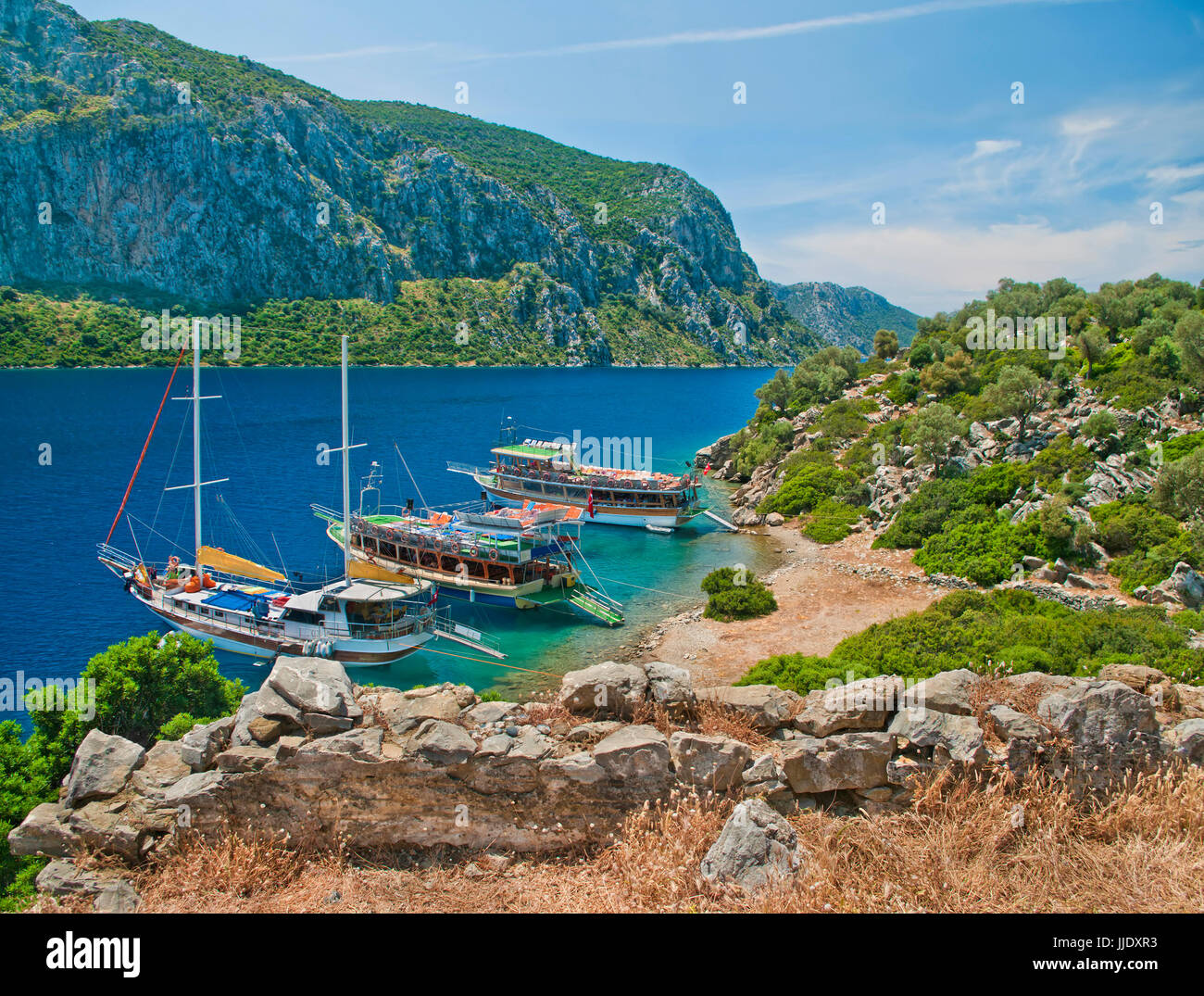 Vista de tres barcos turísticos en la isla de camelia en el Mar Egeo desde las ruinas medievales de la pared con las montañas al fondo, Marmaris Turquía Foto de stock
