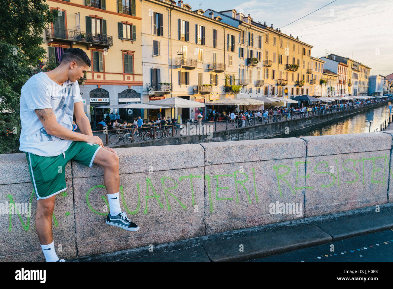 Joven apuesto hombre (20-25) relajándose en Milan, Italia bohemio distrito naviligi al atardecer Foto de stock