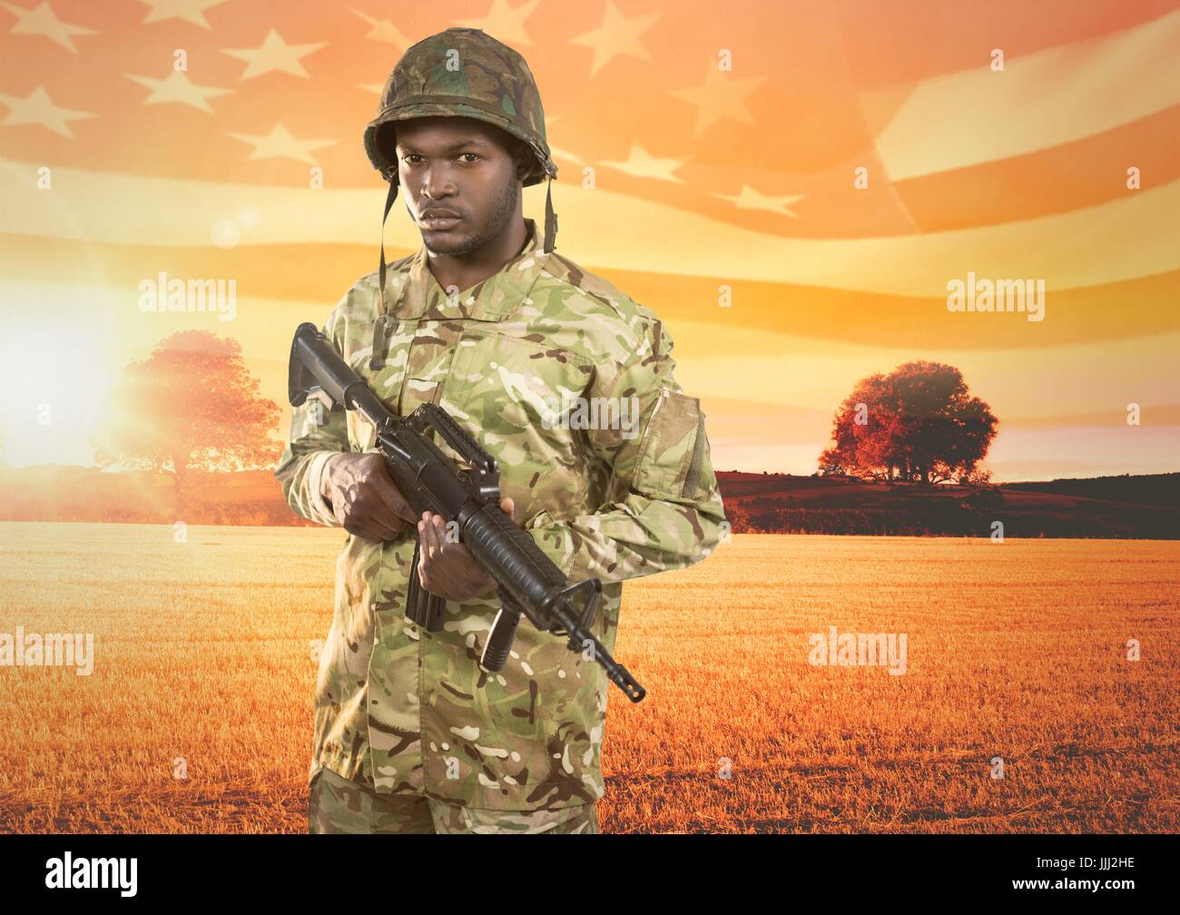 Soldado sosteniendo un arma en frente del campo Foto de stock