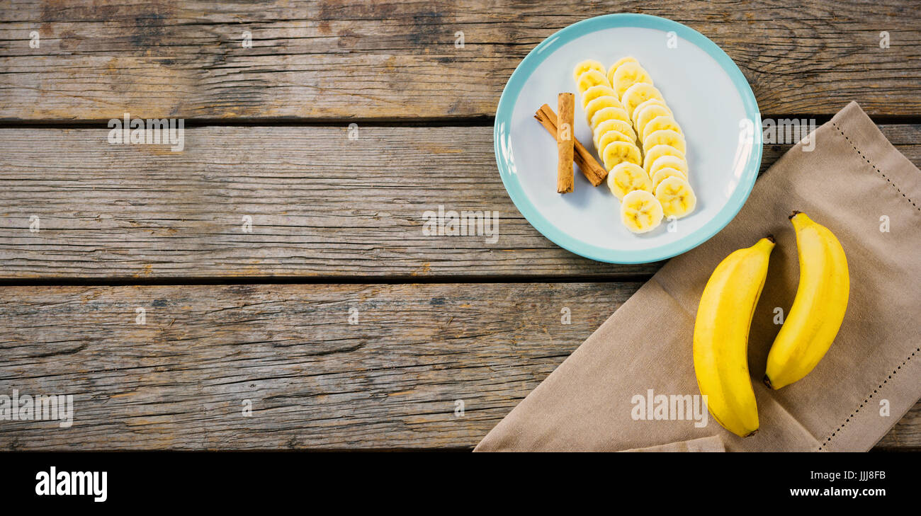 Rodajas de plátano en la placa sobre la mesa de madera Foto de stock