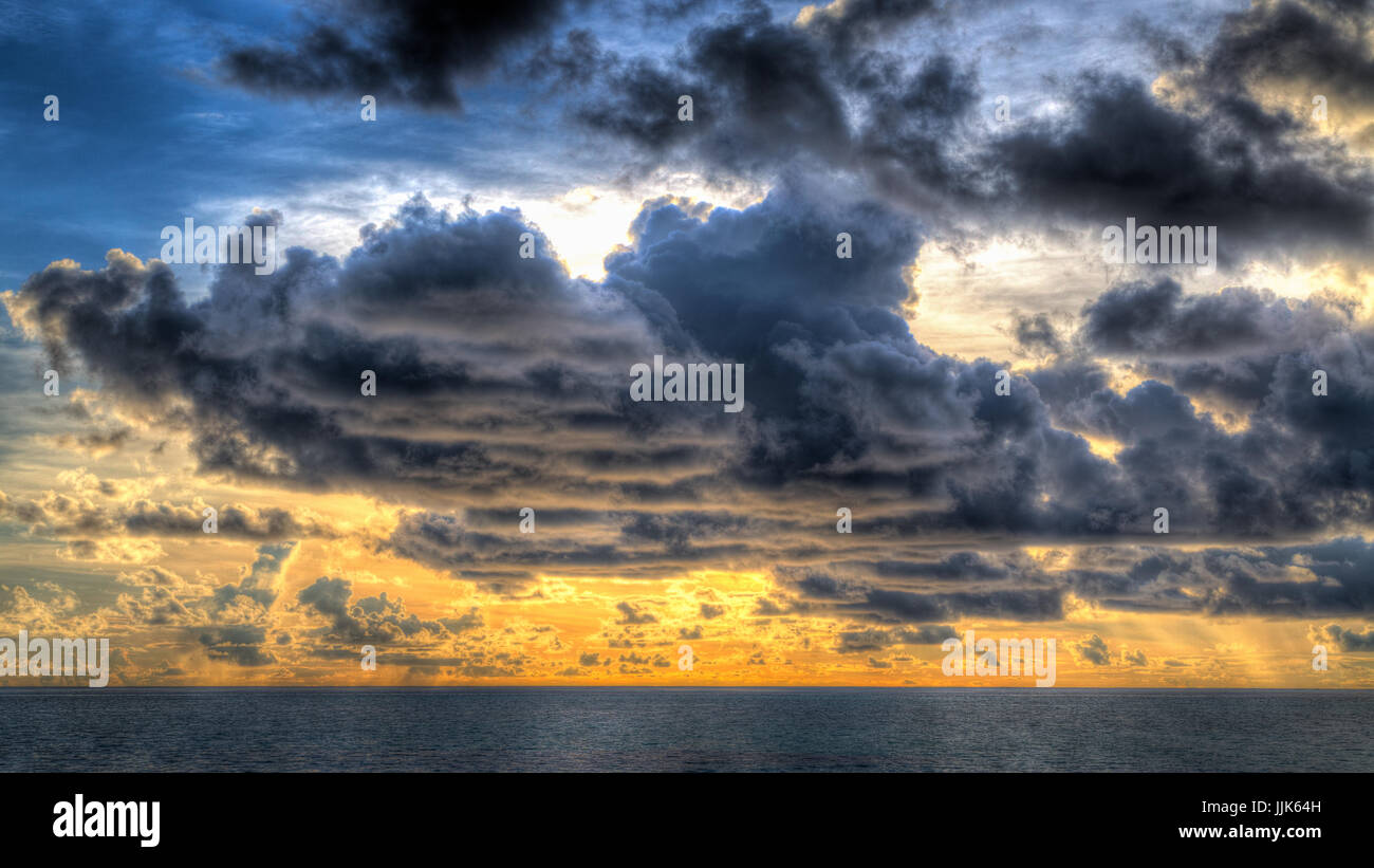 La puesta de sol sobre el mar, el cielo nublado, Gangehi Island, Ari Atoll, Maldivas, Océano Índico Foto de stock