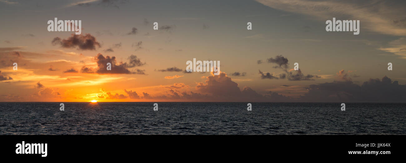 Puesta de sol, el sol hundiéndose en el mar, el cielo nublado, Gangehi Island, Ari Atoll, Maldivas, Océano Índico Foto de stock