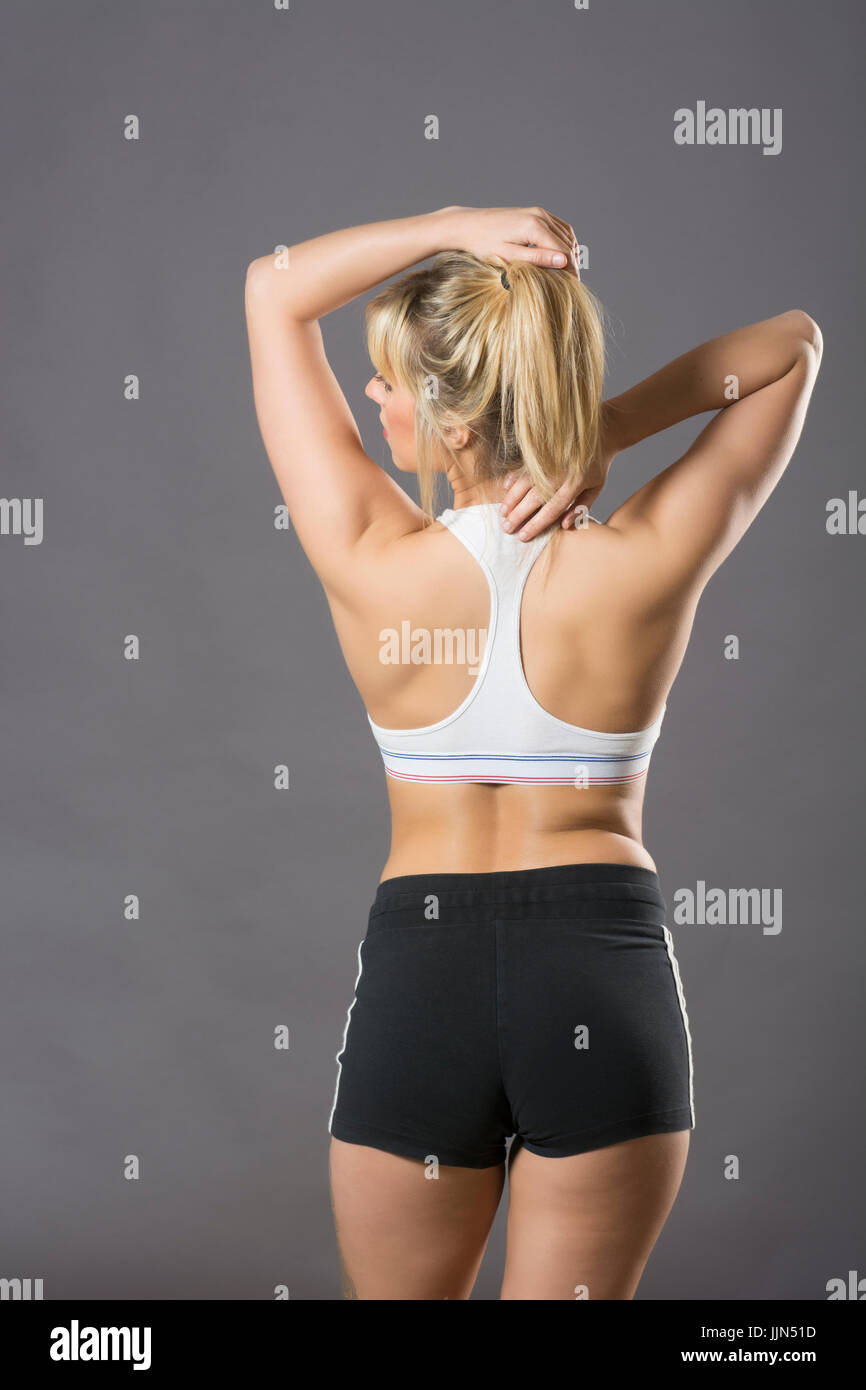 Vista trasera de una mujer vistiendo un sujetador deportivo y corta las  manos en la cabeza Fotografía de stock - Alamy