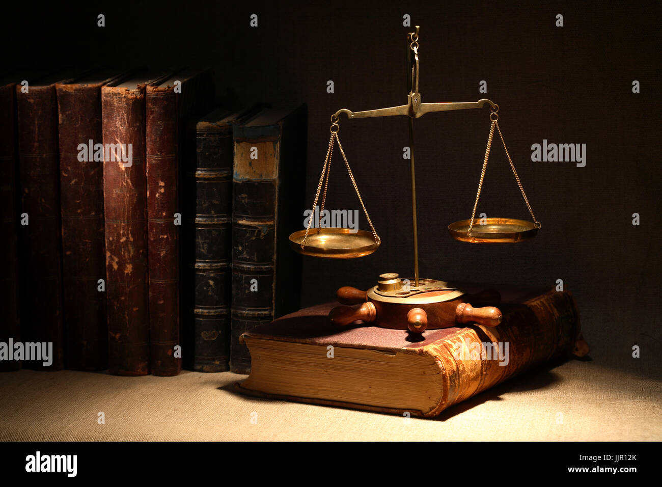 Concepto de legislación. Báscula de latón antiguo y libros antiguos bajo el haz de luz sobre un fondo oscuro Foto de stock