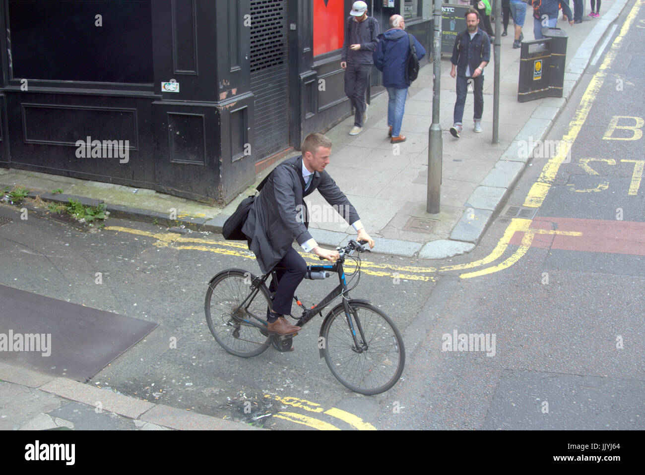 Un trabajador de una oficina bien vestidas ciclista saliendo por un camino lateral doble amarilla de líneas desde arriba Hope Street Glasgow Foto de stock