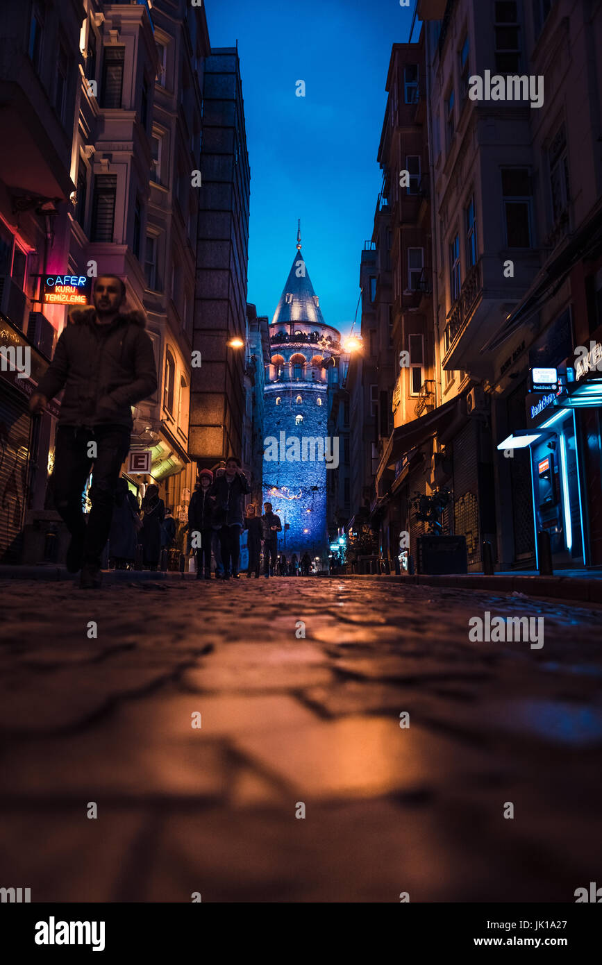 Vista nocturna de la vieja calle estrecha con la torre de Galata(Turco: Galata Kulesi)llamado Cristo Torre por genovés, un famoso monumento medieval en Estambul. Foto de stock