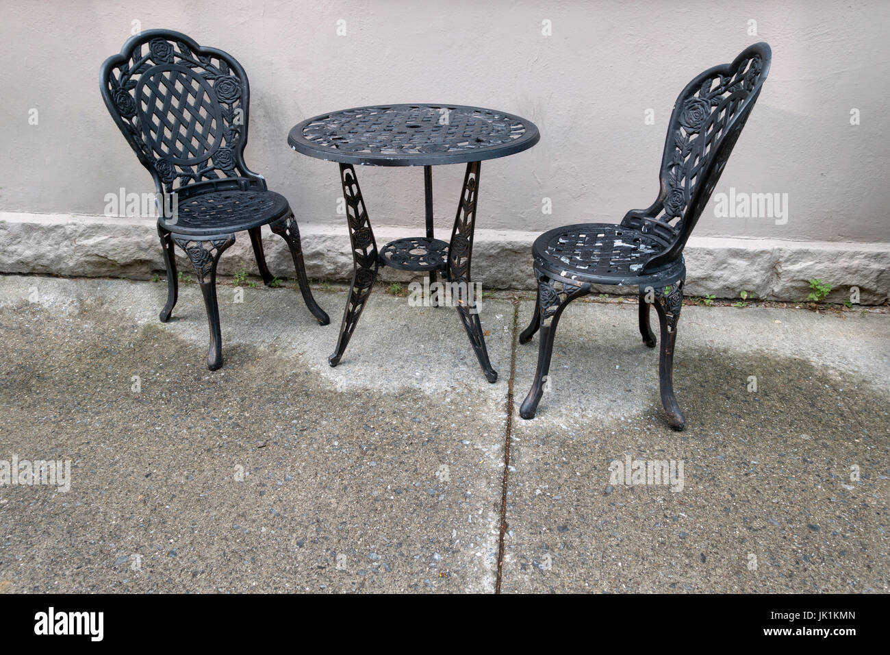 Hierro fundido negro mesa y sillas exterior piso mojado. Foto de stock
