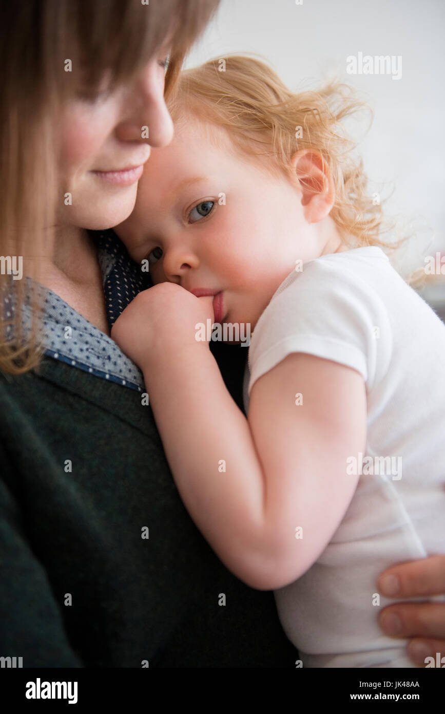 Madre sosteniendo caucásica hija chuparse el pulgar Foto de stock