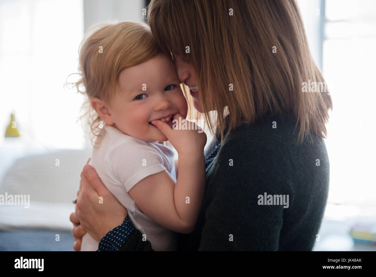 Madre sosteniendo caucásica hija sonriente Foto de stock