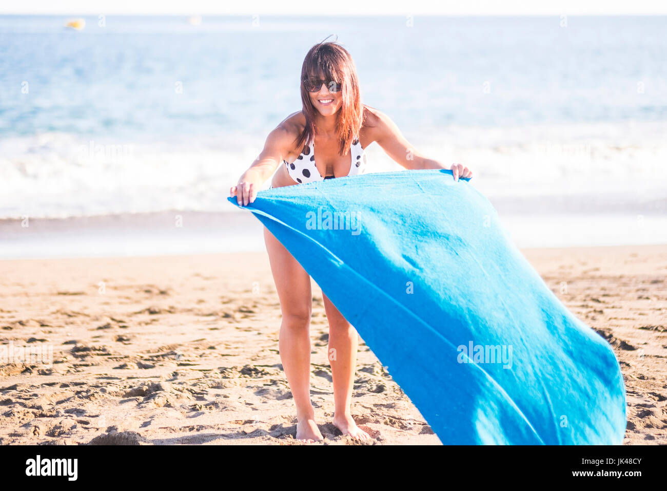 Mujer caucásica extendiendo una manta en la playa Foto de stock