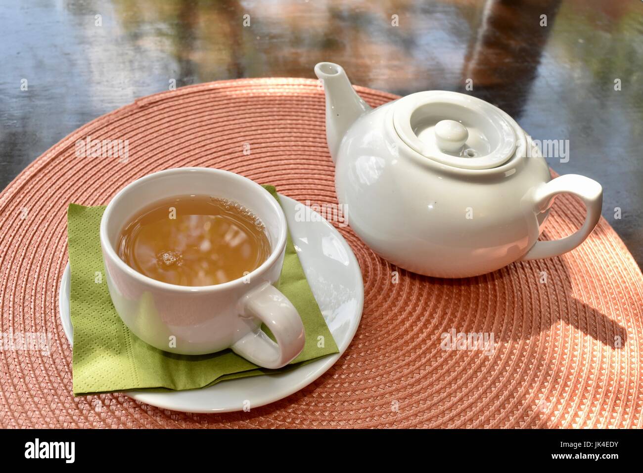Servicio de té con olla y taza llena de té en una tabla en el Té Haus en Ann Arbor, Michigan, en día soleado. Foto de stock