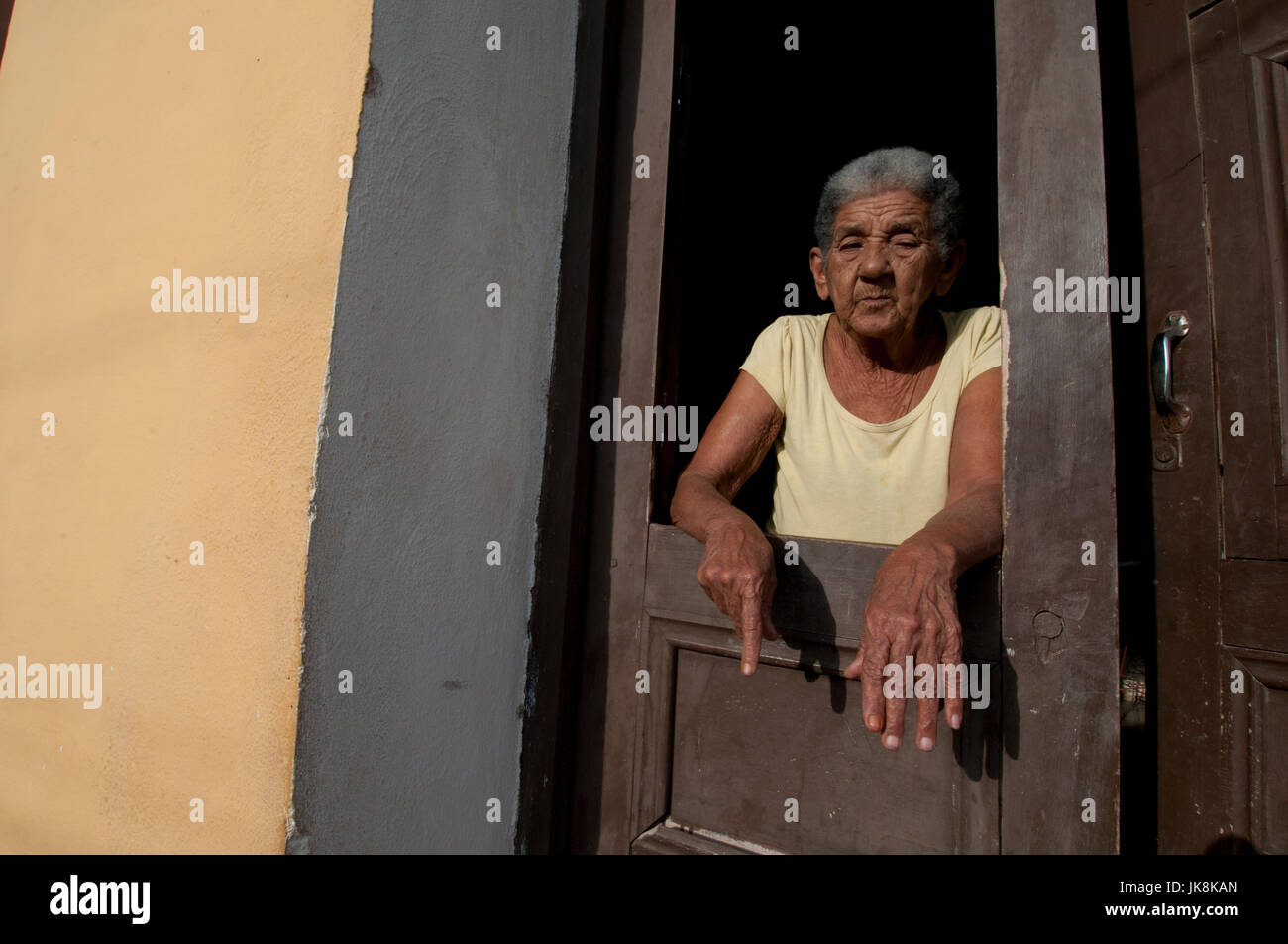 Ancianos mujer cubana de pie en su puerta en las primeras horas de la noche en Trinidad, Cuba Foto de stock