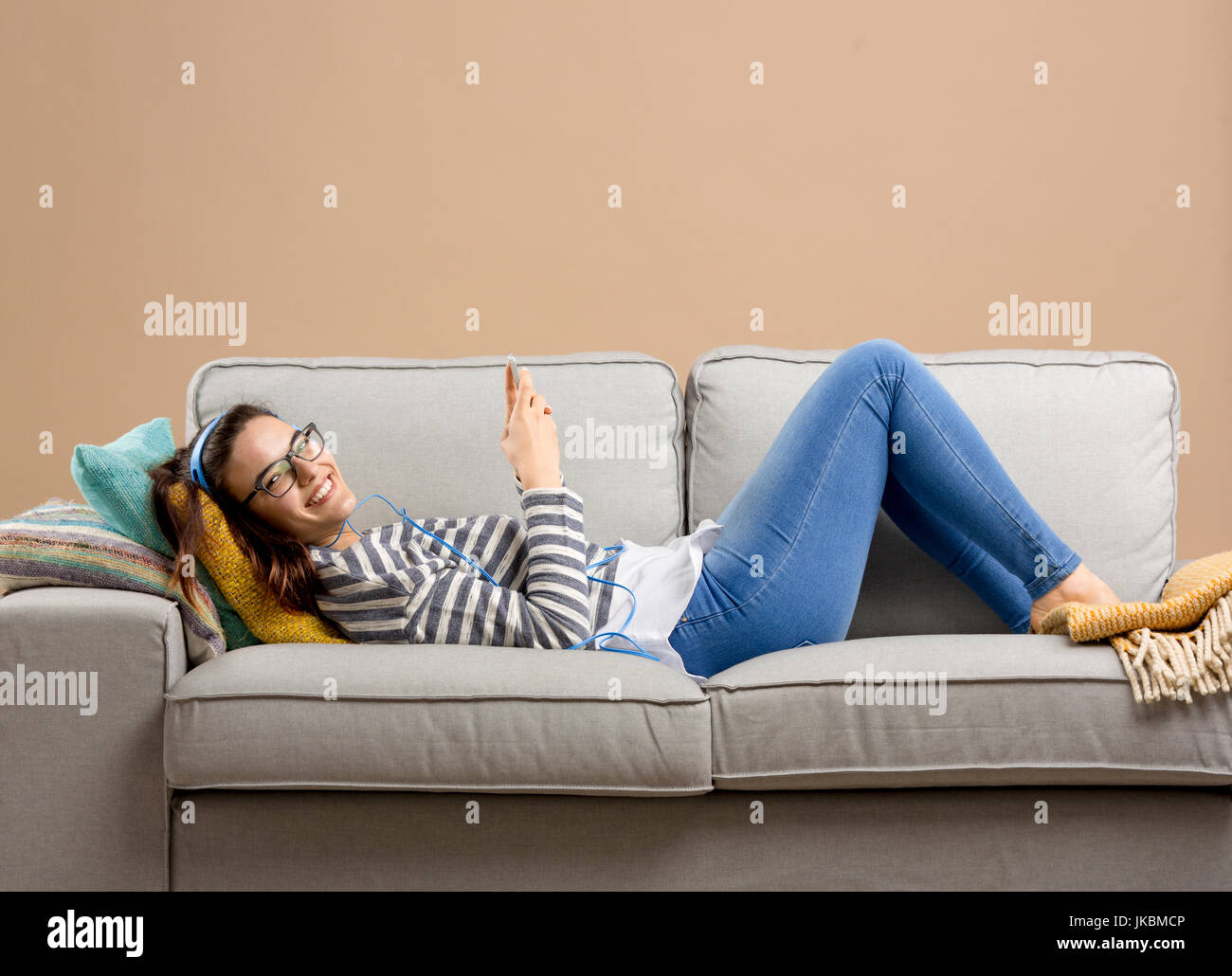 Bella mujer en casa tumbado en el sofá y escuchar música Foto de stock