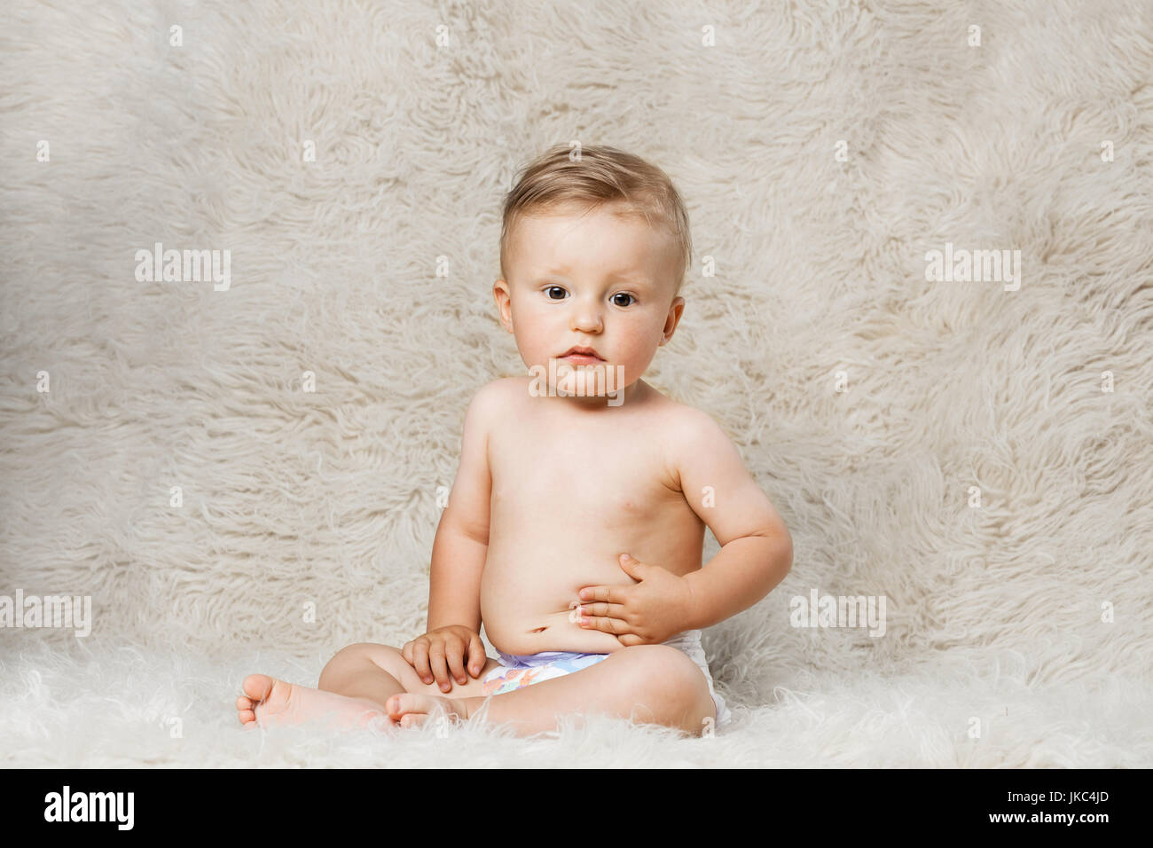 Baby Boy en pañales, sentada sobre una manta de lana shaggy caseros Foto de stock