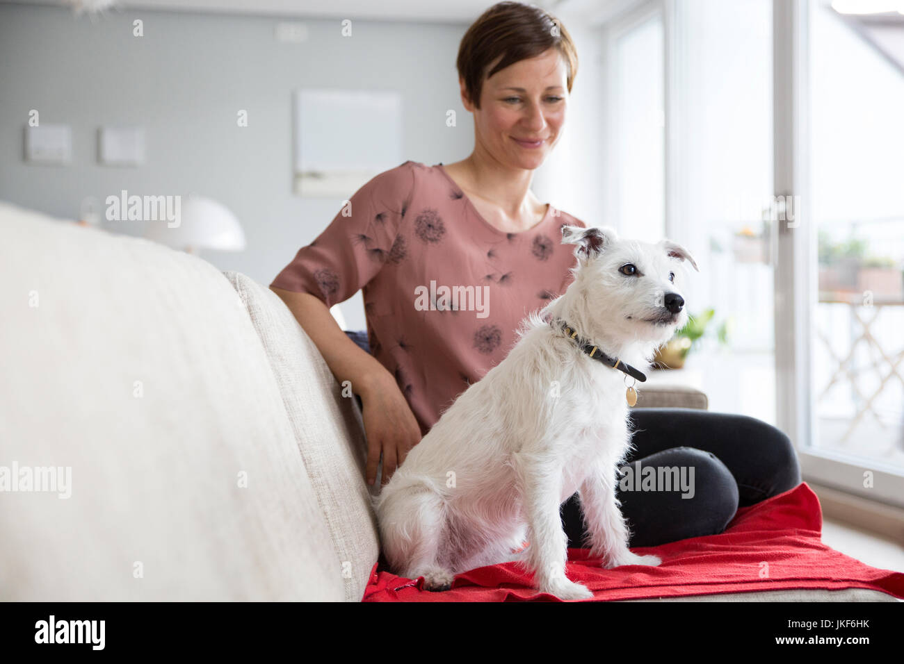 Mujer y su perro sentados juntos en el sofá Foto de stock