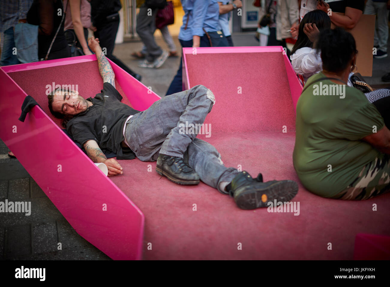 Manhattan, Ciudad de Nueva York, Estados Unidos, el hombre durmiendo entre los turistas en rosa moderno mobiliario urbano bancos Foto de stock