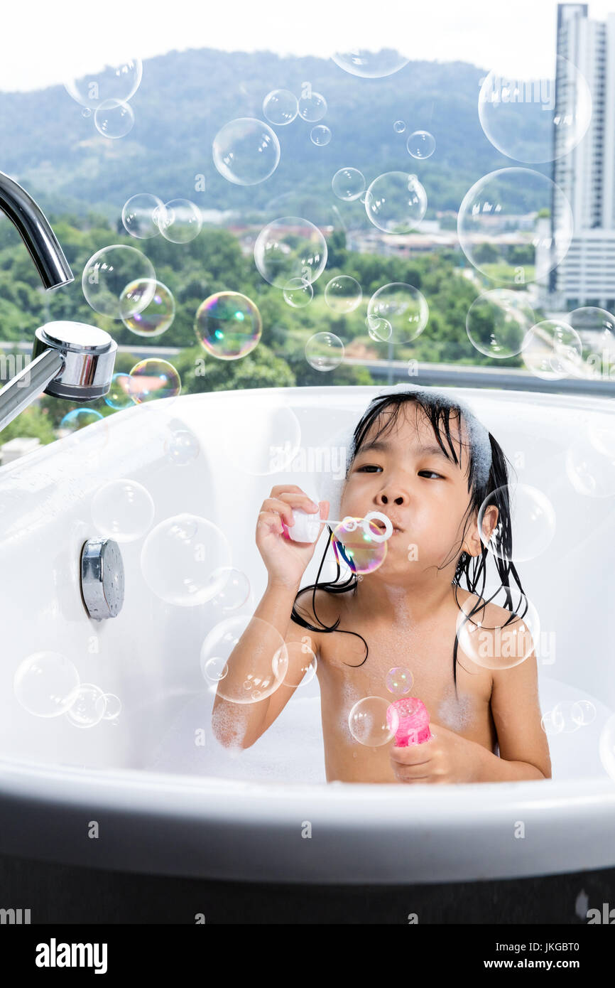 Niña China Asia soplando burbujas en la bañera en casa Fotografía de stock  - Alamy