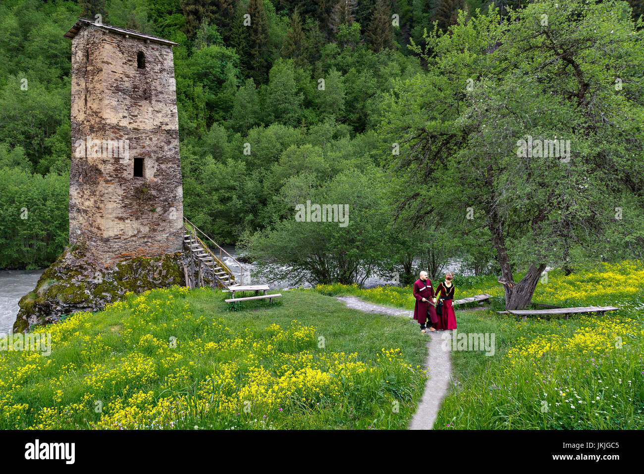 Hombre y mujer georgiana en trajes nacionales, cerca de una torre medieval, Georgia. Foto de stock