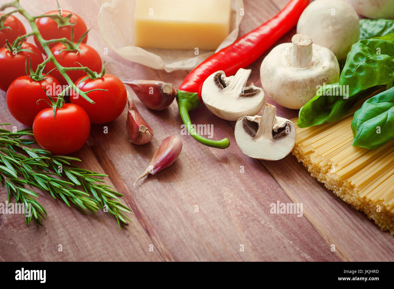 Montón de spaghetti italiano closeup con champiñones y tomates en una rústica cocina en una mesa de madera. En el modo de fondo, chef de tomate troceado para co Foto de stock