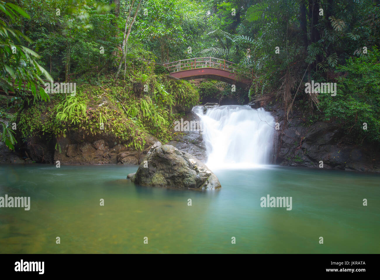 Un paisaje íntimo de una impresionante cascada y estanque de agua pura, rodeado por el verde de la vegetación. Ranchan Cascada, Sarawak en Malasia. Foto de stock