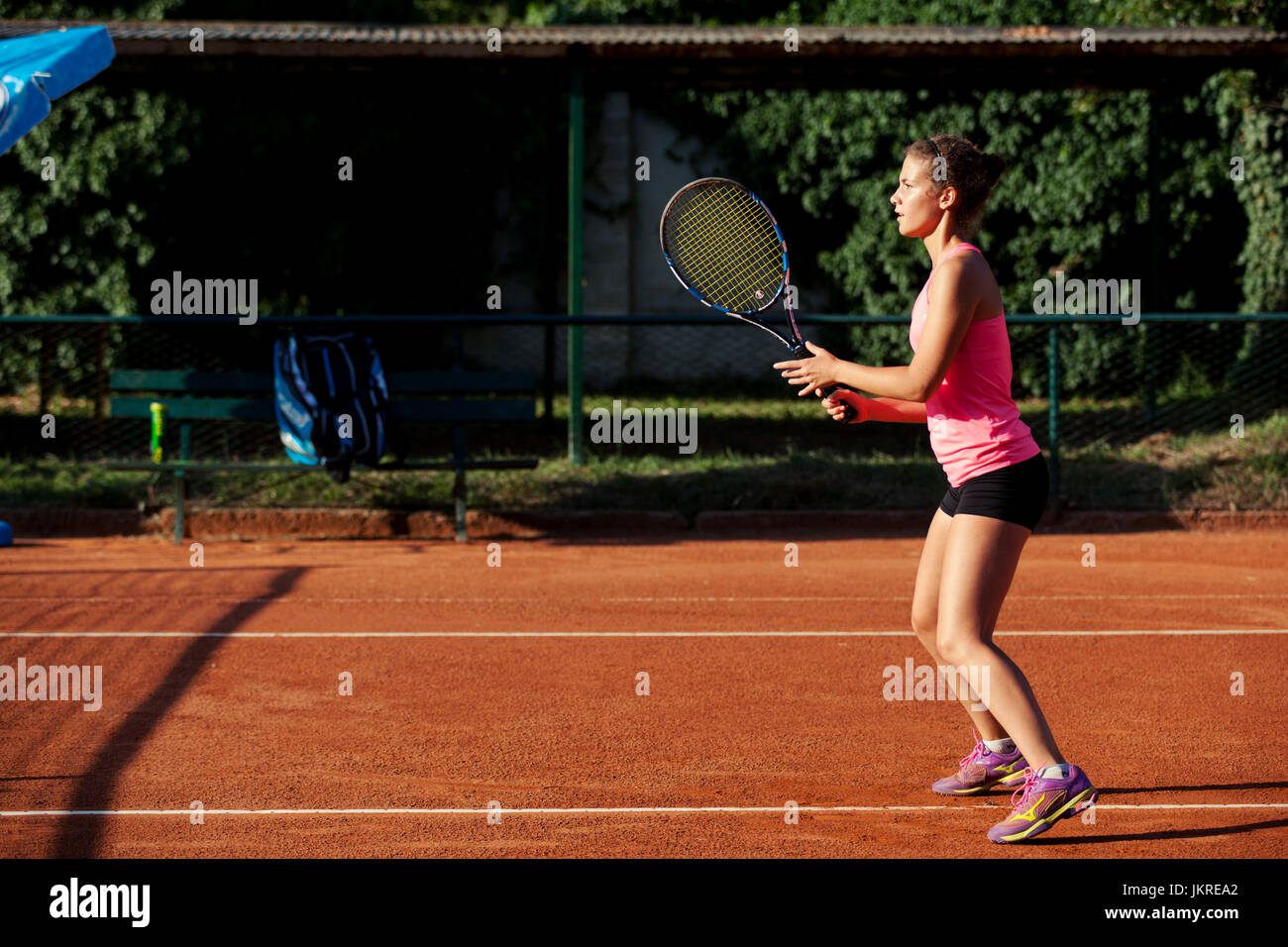 Niña jugando a tenis en la cancha de arcilla roja Foto de stock