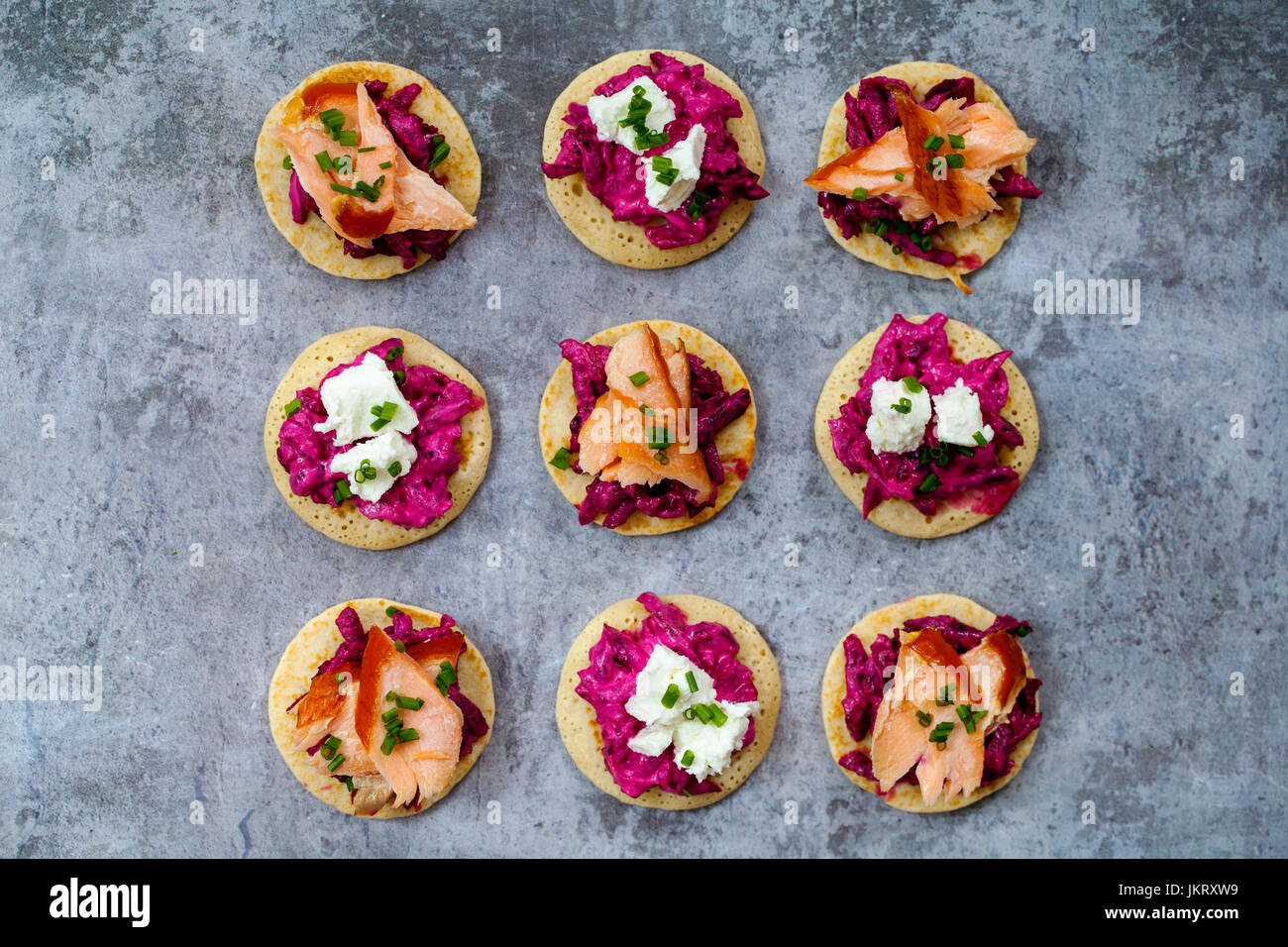 Blinis con remolacha, rábano picante, salmón ahumado en caliente y cabra chhese Foto de stock