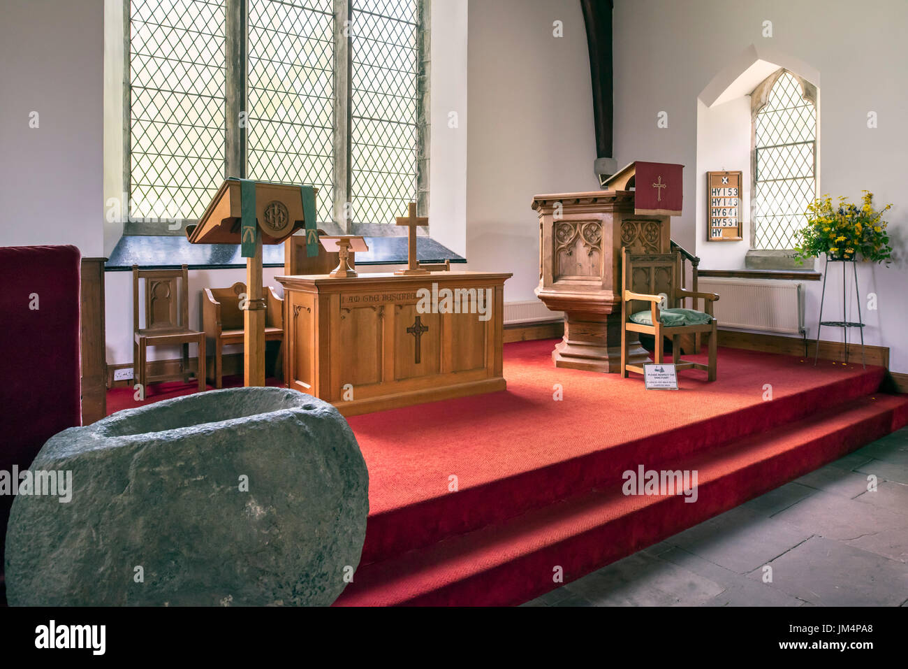 Pila bautismal de piedra mostrando interior, el altar y el púlpito de madera de la Iglesia Parroquial de Balquhidder, Stirling, Escocia, Reino Unido Foto de stock
