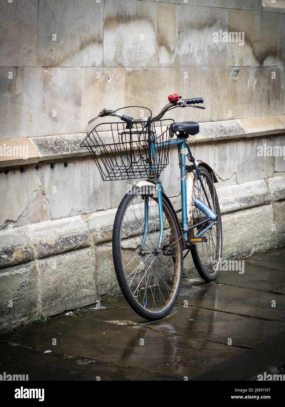 Estudiante de bicicletas - un estudiante bike se inclina contra una pared central college en Cambridge, Reino Unido Foto de stock