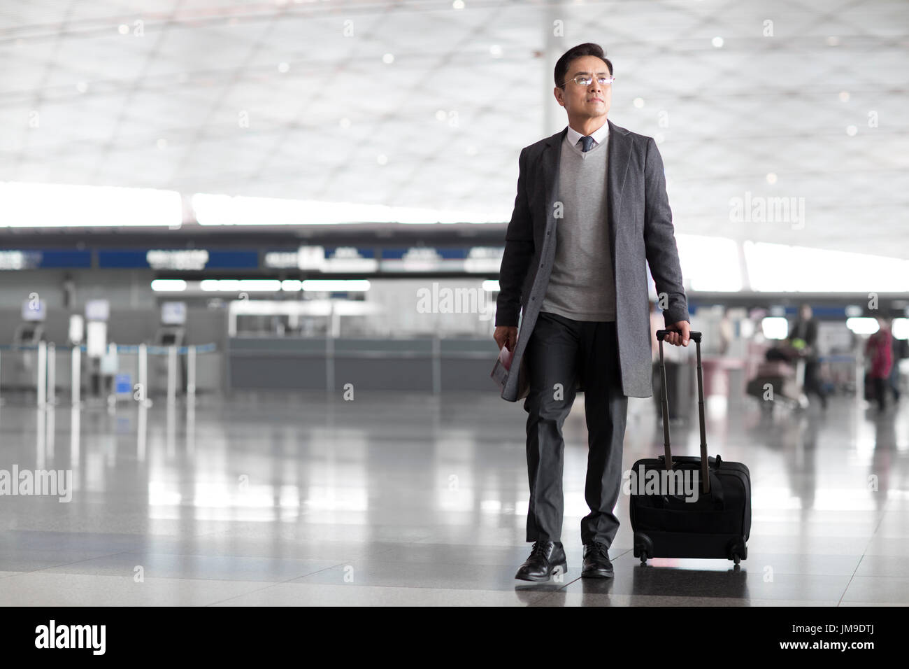 Los empresarios chinos jalando maletas con ruedas en el vestíbulo del  aeropuerto Fotografía de stock - Alamy