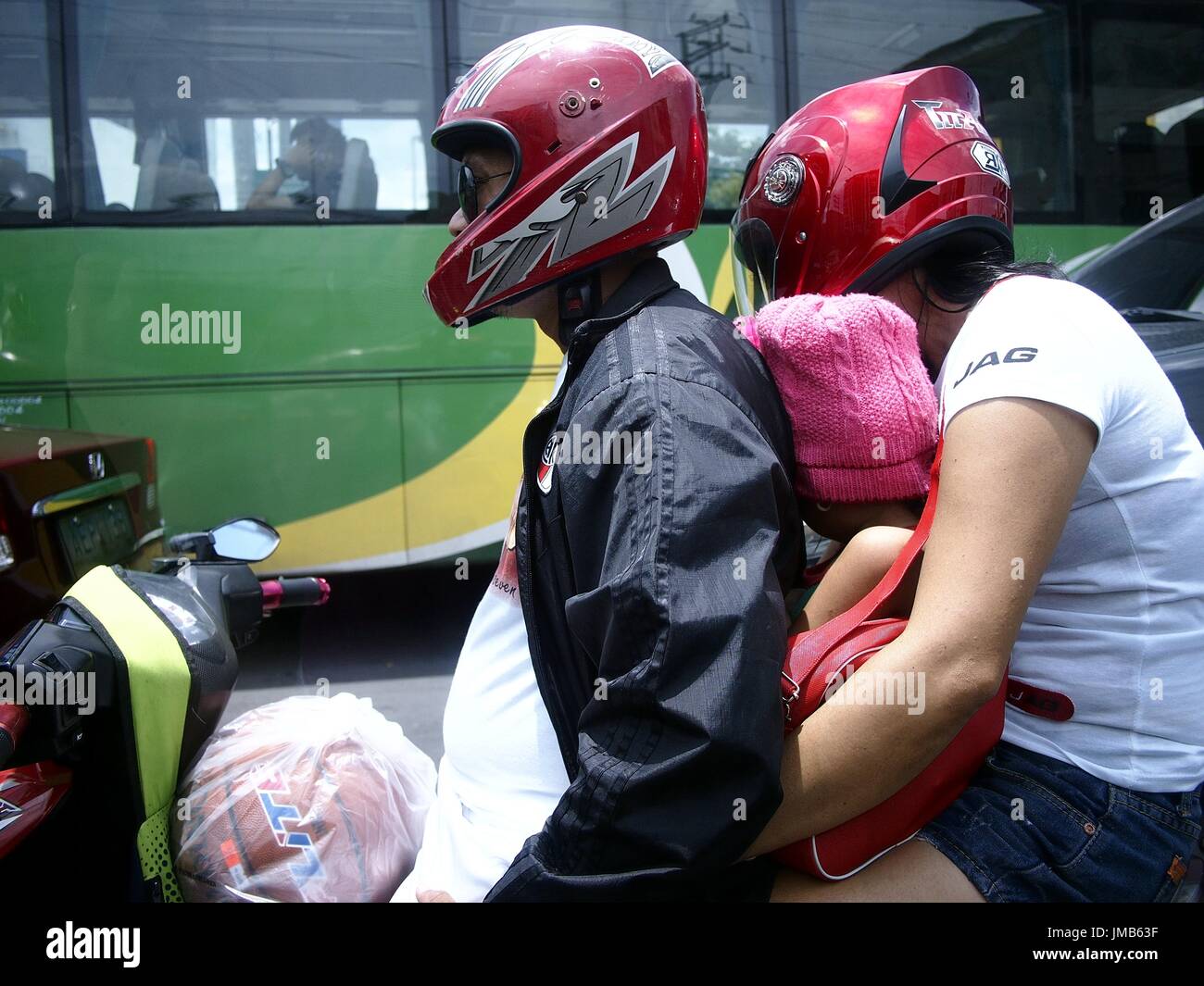 ANTIPOLO CITY, Filipinas - Julio 21, 2017: un padre y una madre con su hijo andar en motocicleta. Foto de stock