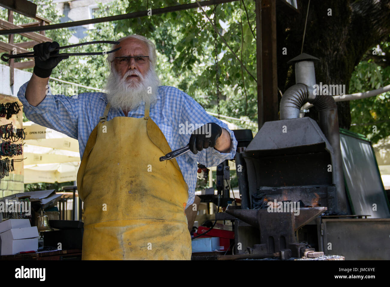 Cetinje, Montenegro - anciano herrero haciendo recuerdos de herradura y entretener a los turistas en un taller de la calle Foto de stock