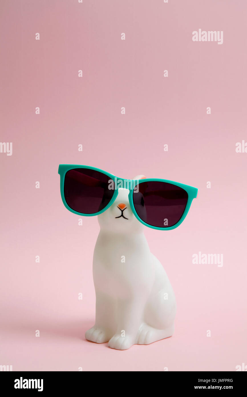 Un lindo conejito de plástico blanco con gafas de sol sobre un fondo de  color rosa. La fotografía de modos de vida color mínimo Fotografía de stock  - Alamy